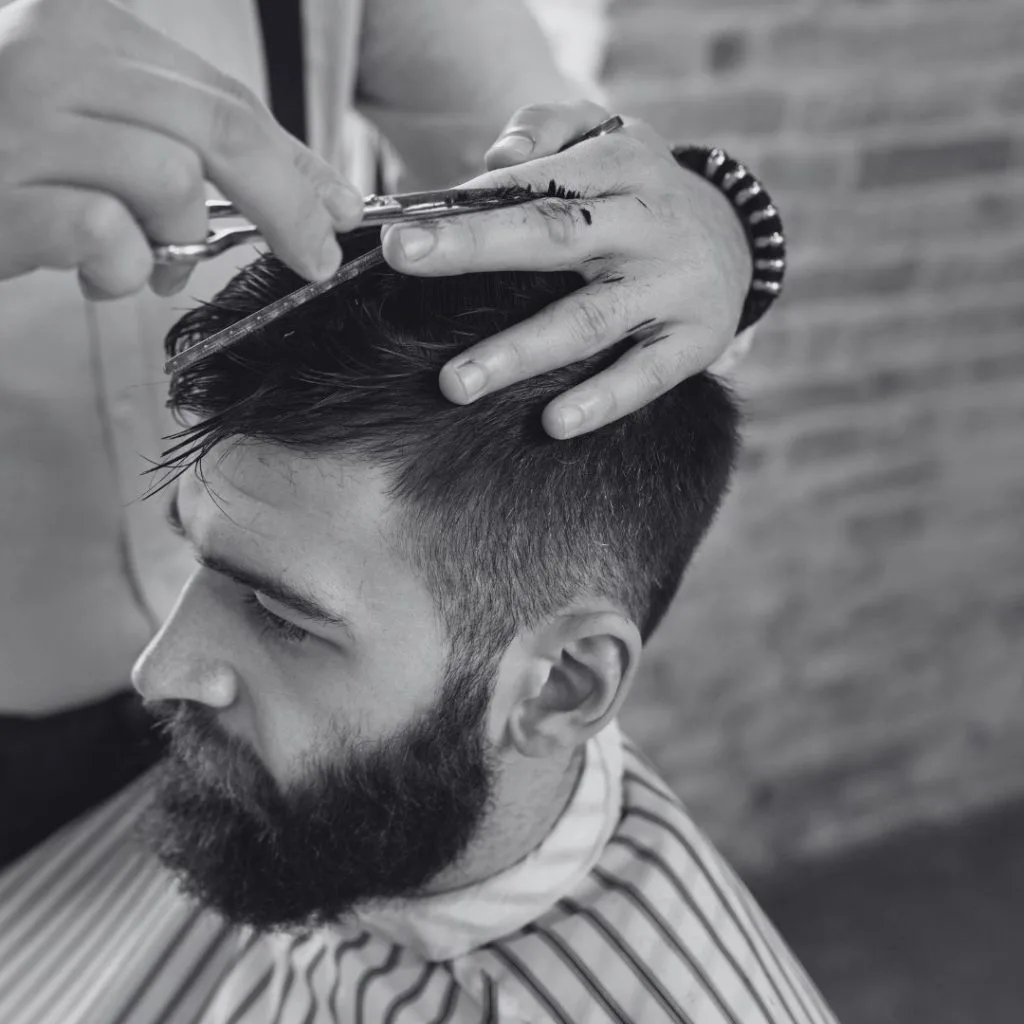 Homme barbu coiffé aux ciseaux et au peigne par un coiffeur