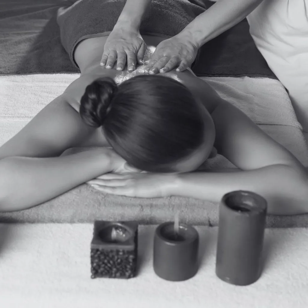 Massage du dos à l'huile, bougies posées au premier plan