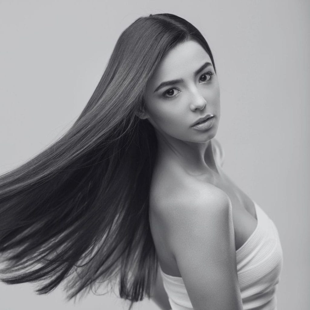 Portrait en noir et blanc d’une femme aux longs cheveux lisses en mouvement.