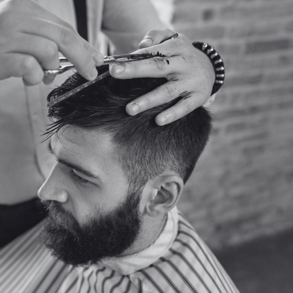 Un homme barbu coiffé aux ciseaux et au peigne.