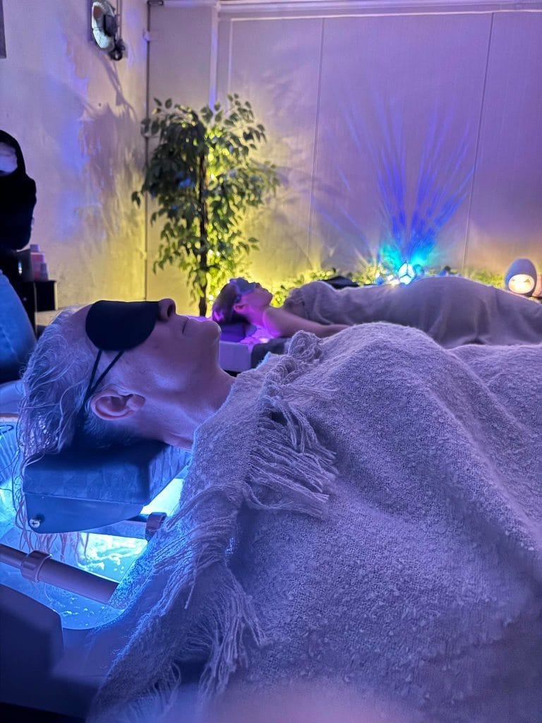 Head Spa en duo : deux personnes allongées côte à côte, chacune dans son bac, un masque sur les yeux et un plaid sur les épaules, dans la même cabine.